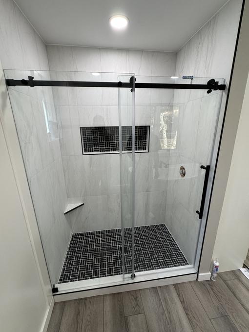 Marble shower behind frameless glass with a basketweave mosaic pan